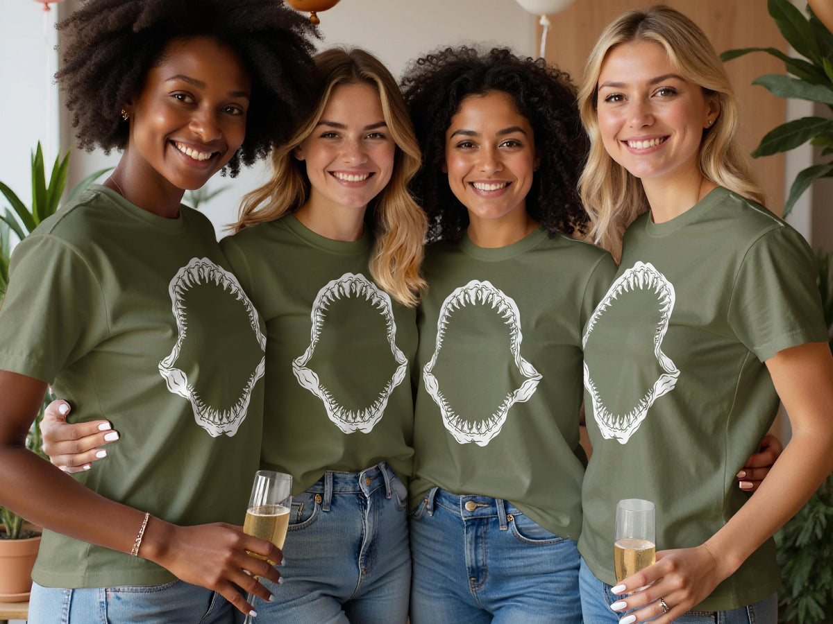 Four women wear olive green t-shirts with shark jaw graphic prints.