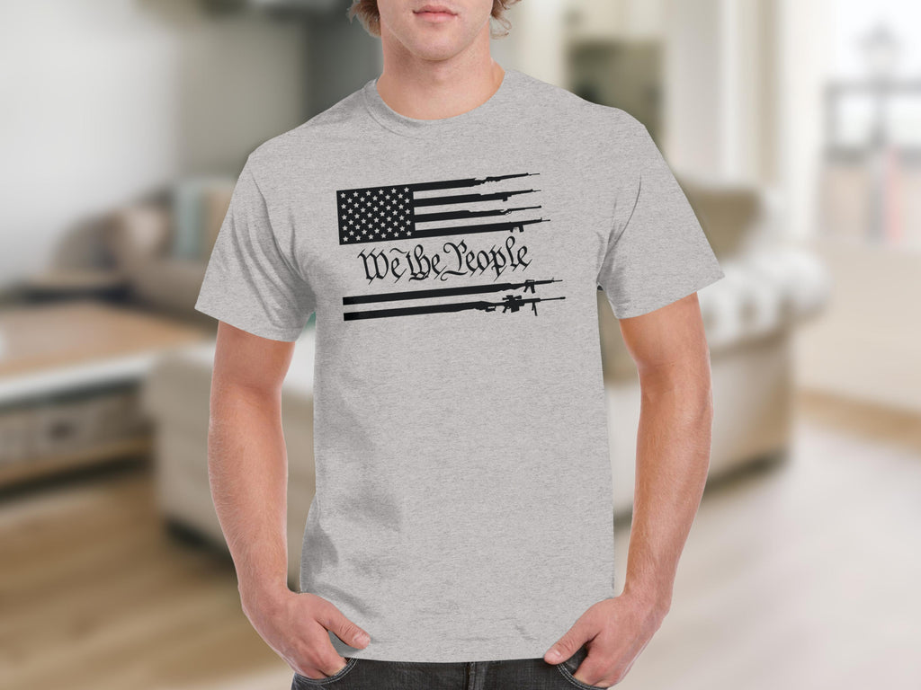 Grey t-shirt with a stylized American flag featuring guns and the text "We the People".