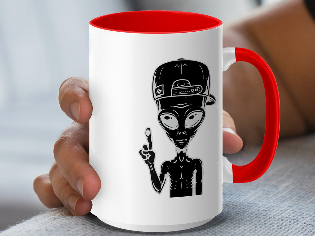 White mug with red handle featuring a black alien graphic wearing a backwards baseball cap.