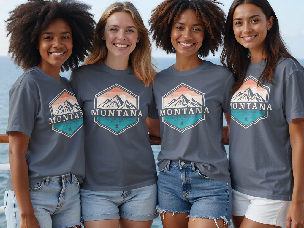 Four women in gray t-shirts with a "Montana Take a Hike" mountain logo stand together.