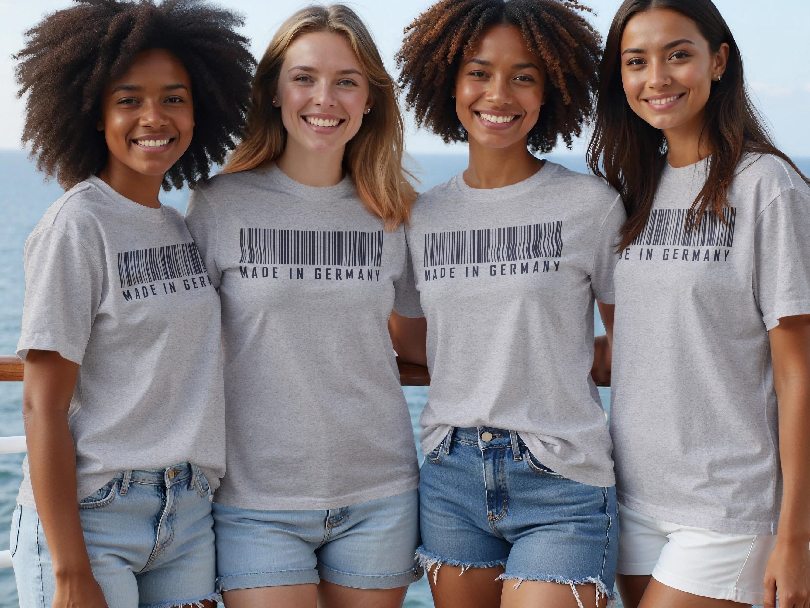 Four young women in grey t-shirts that say "MADE IN GERMANY" with a barcode.