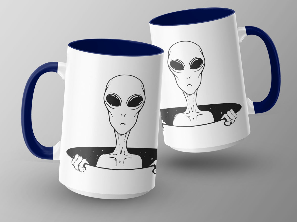 Two white mugs with navy blue handles and interiors featuring a black alien design.