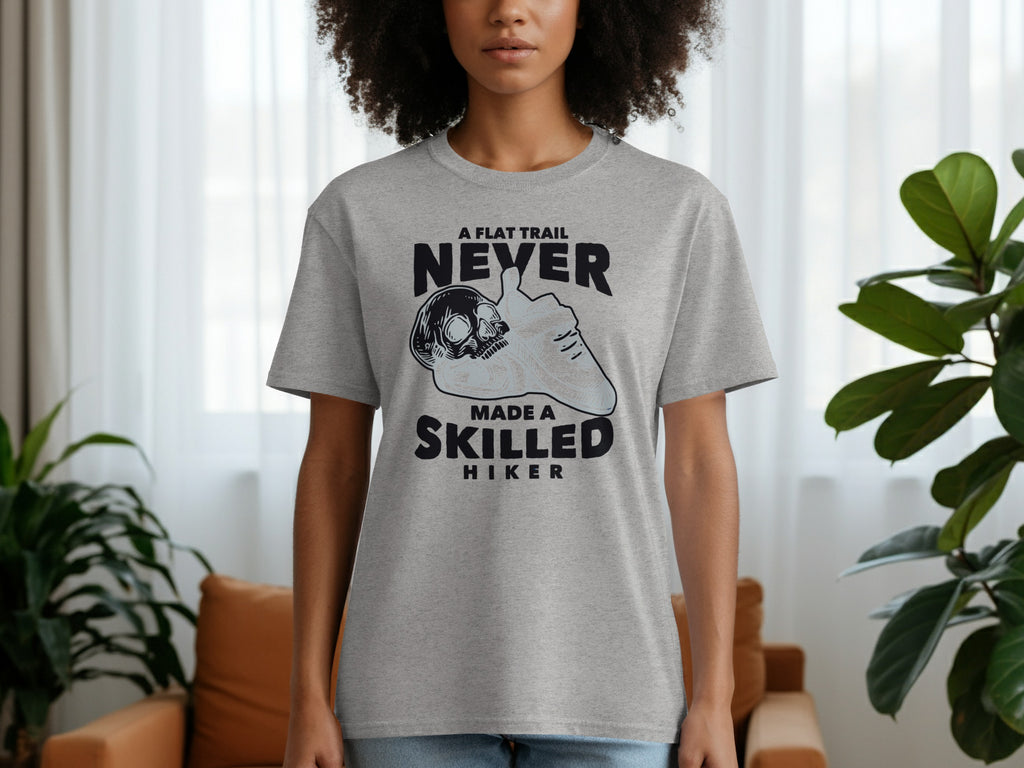 Grey t-shirt with text "A flat trail never made a skilled hiker" and skull graphic