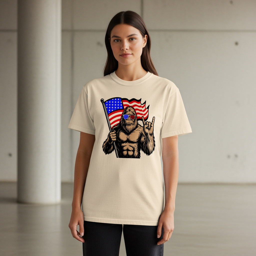 Bigfoot wearing American flag sunglasses holds flag and shows rock on gesture.