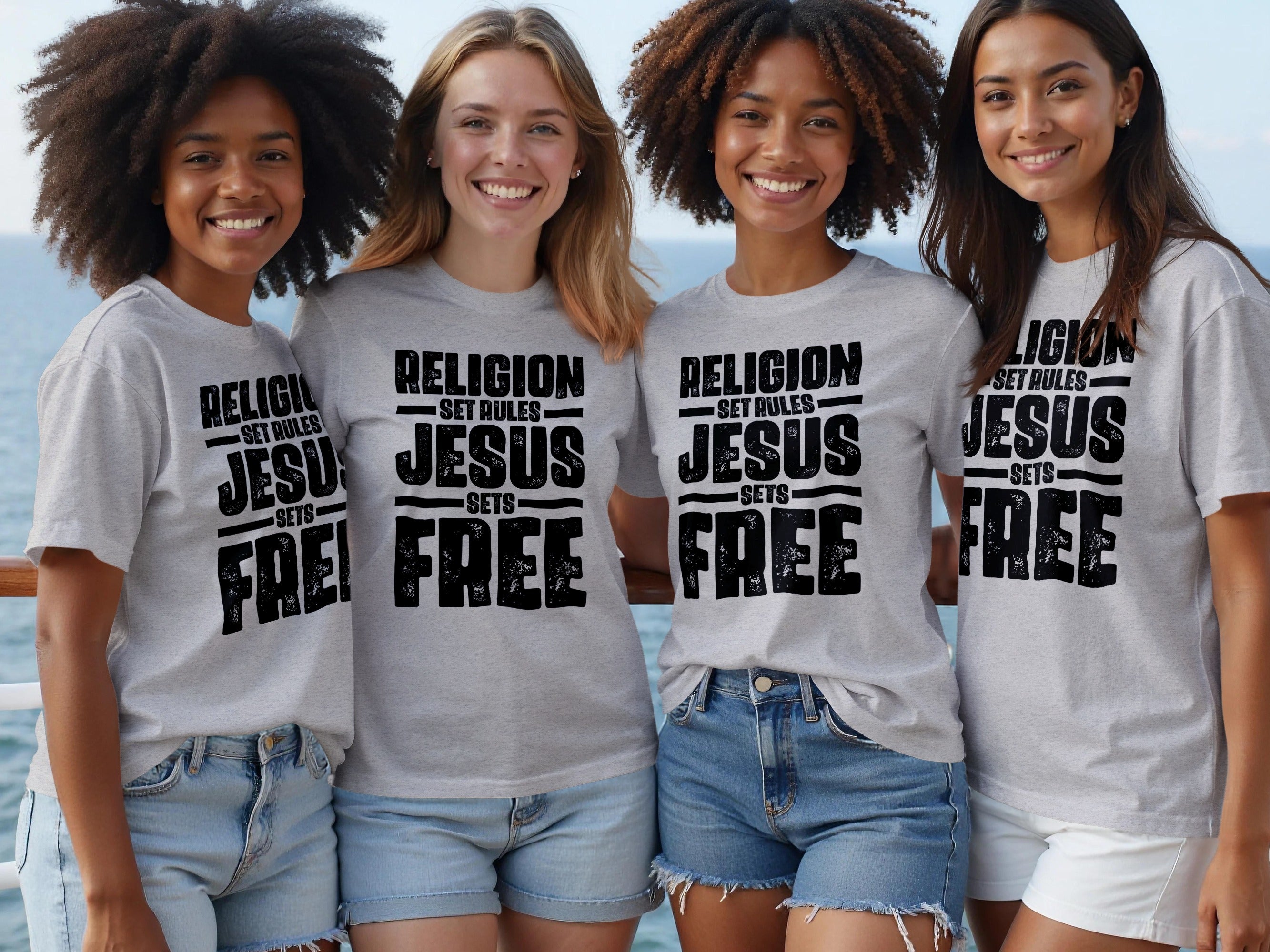 Four smiling women wear grey t-shirts with black text reading "RELIGION SET RULES JESUS SETS FREE".