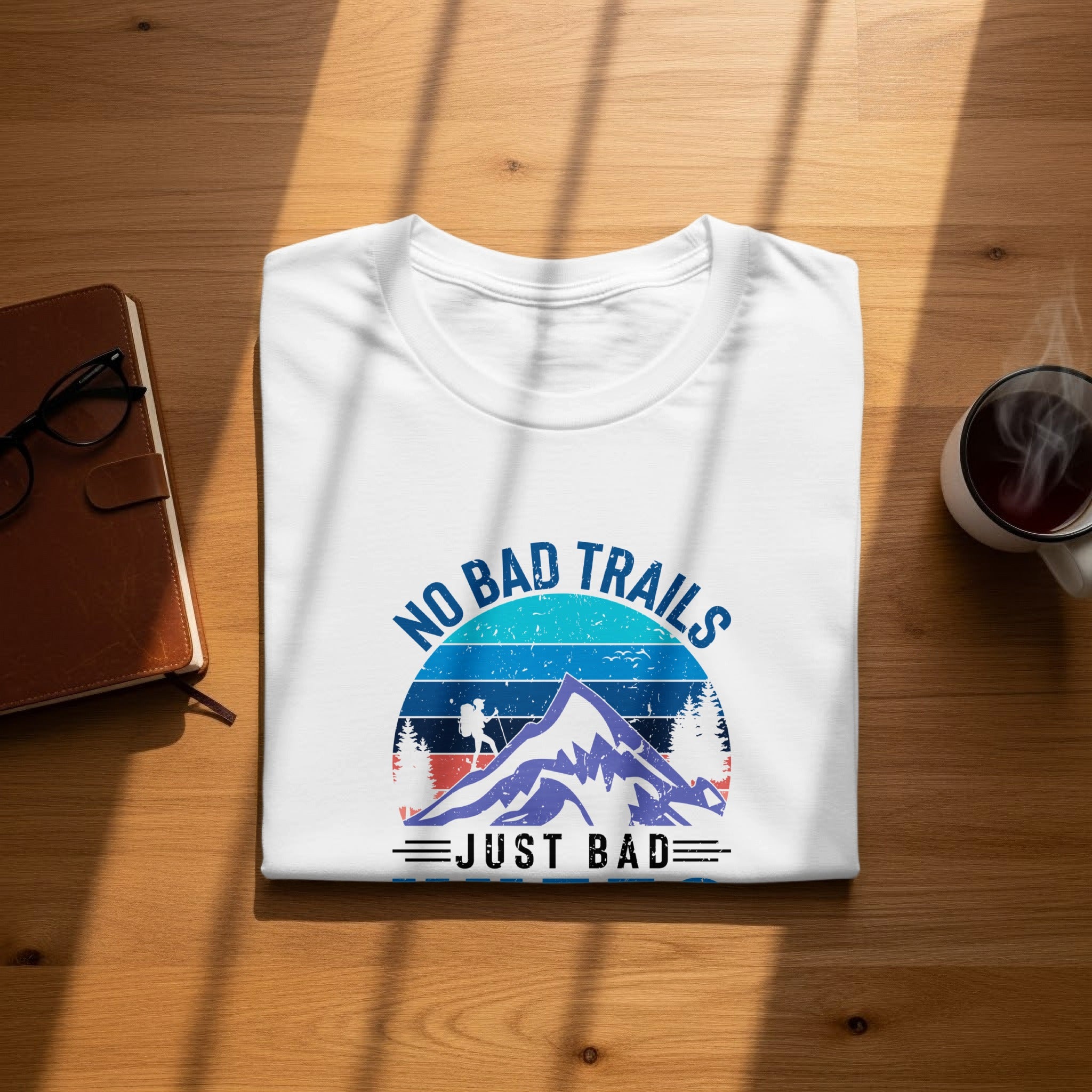 White t-shirt with graphic "No Bad Trails Just Bad" featuring mountains and hiker.