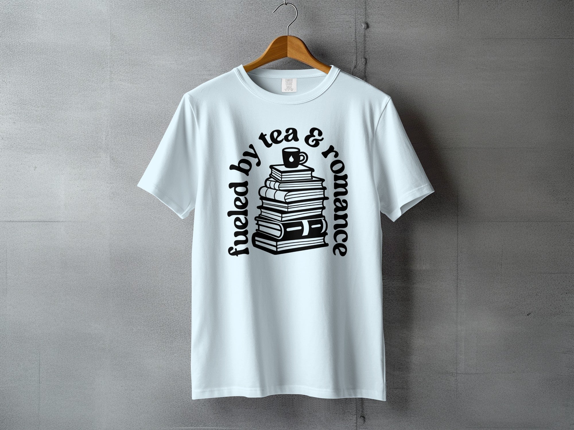 Light blue t-shirt with black text and illustration of stacked books with a tea cup.