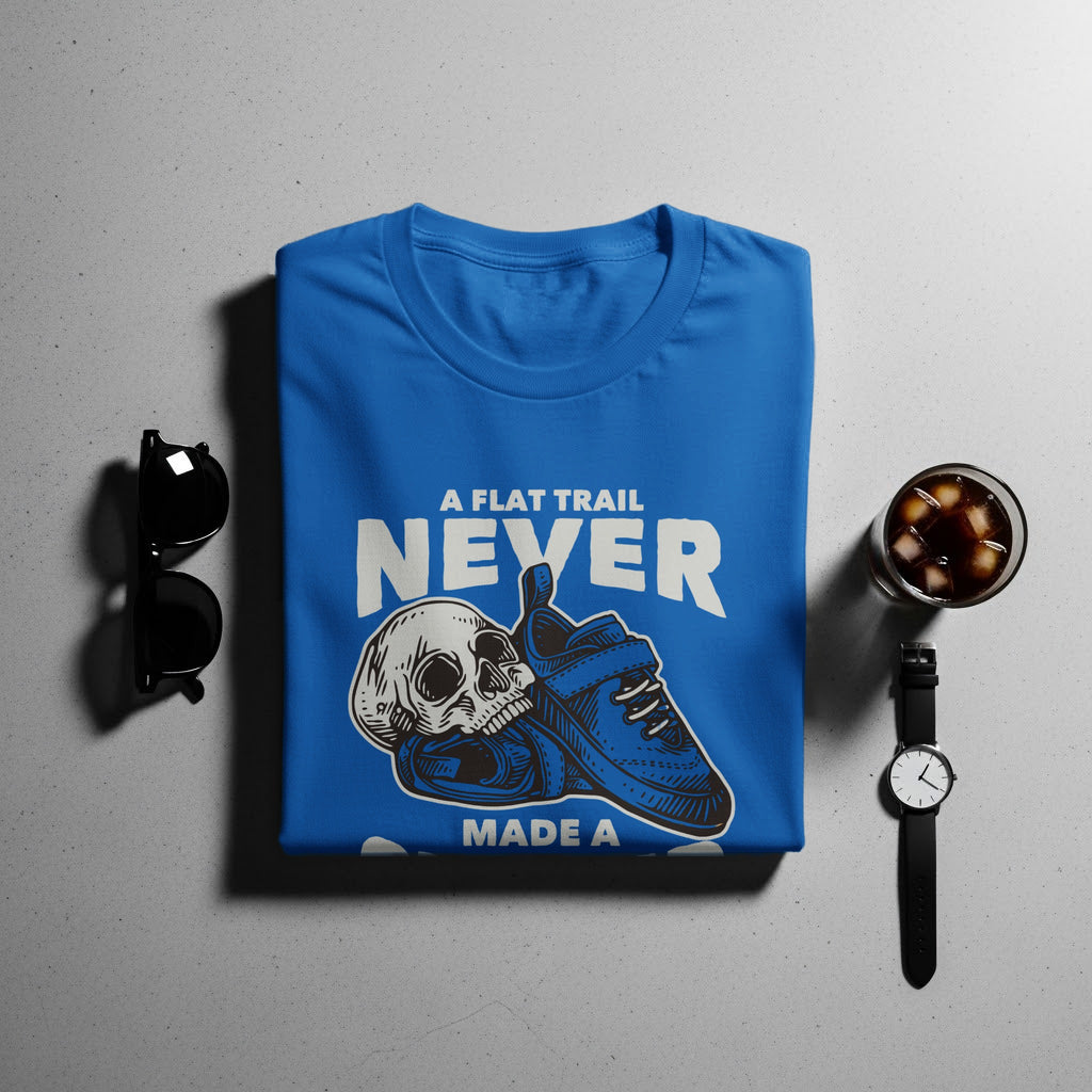 Blue t-shirt with text "A FLAT TRAIL NEVER MADE A" and skull with shoe graphic.