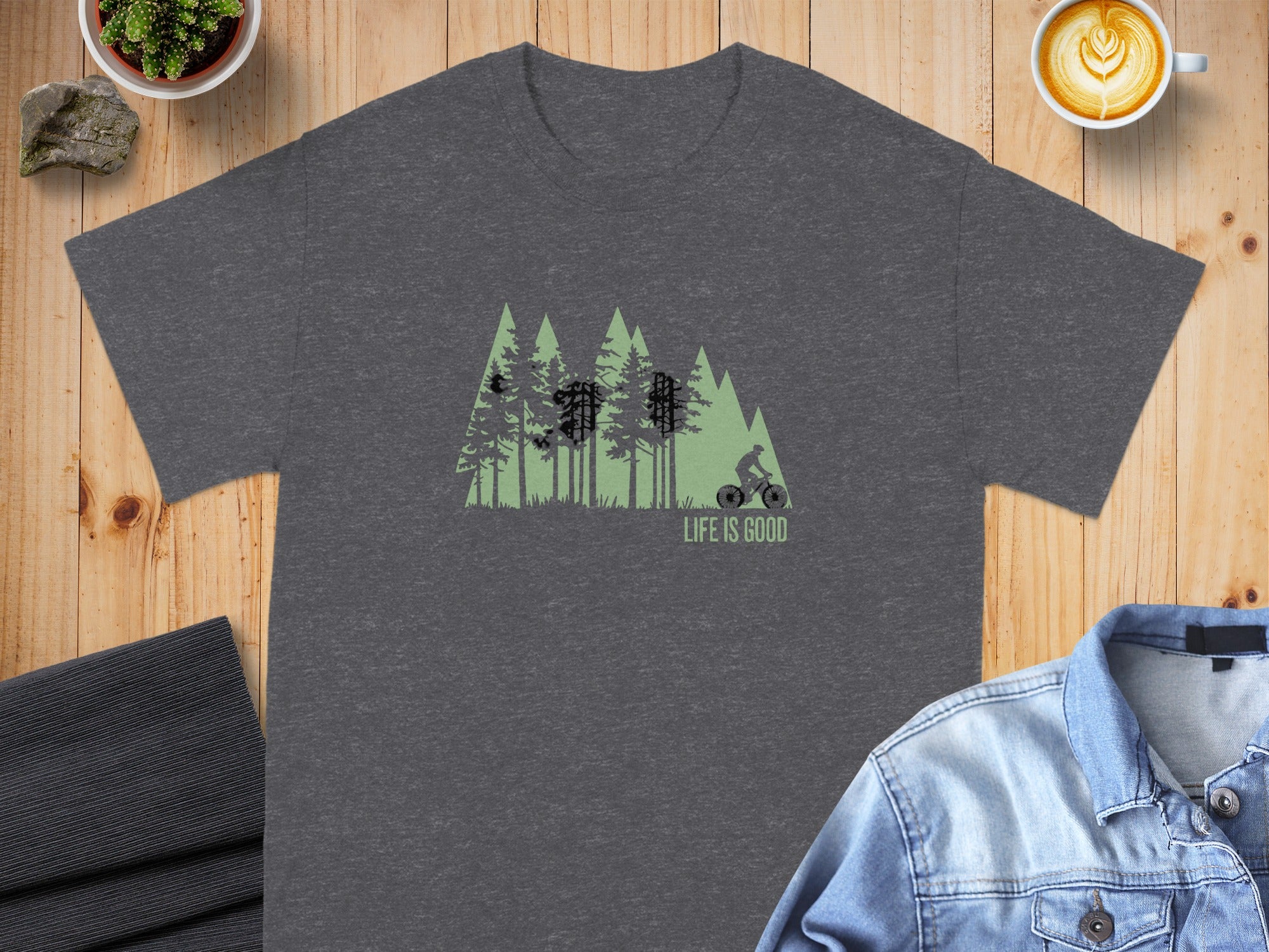 Dark gray t-shirt with a green forest graphic and cyclist, "LIFE IS GOOD" text.