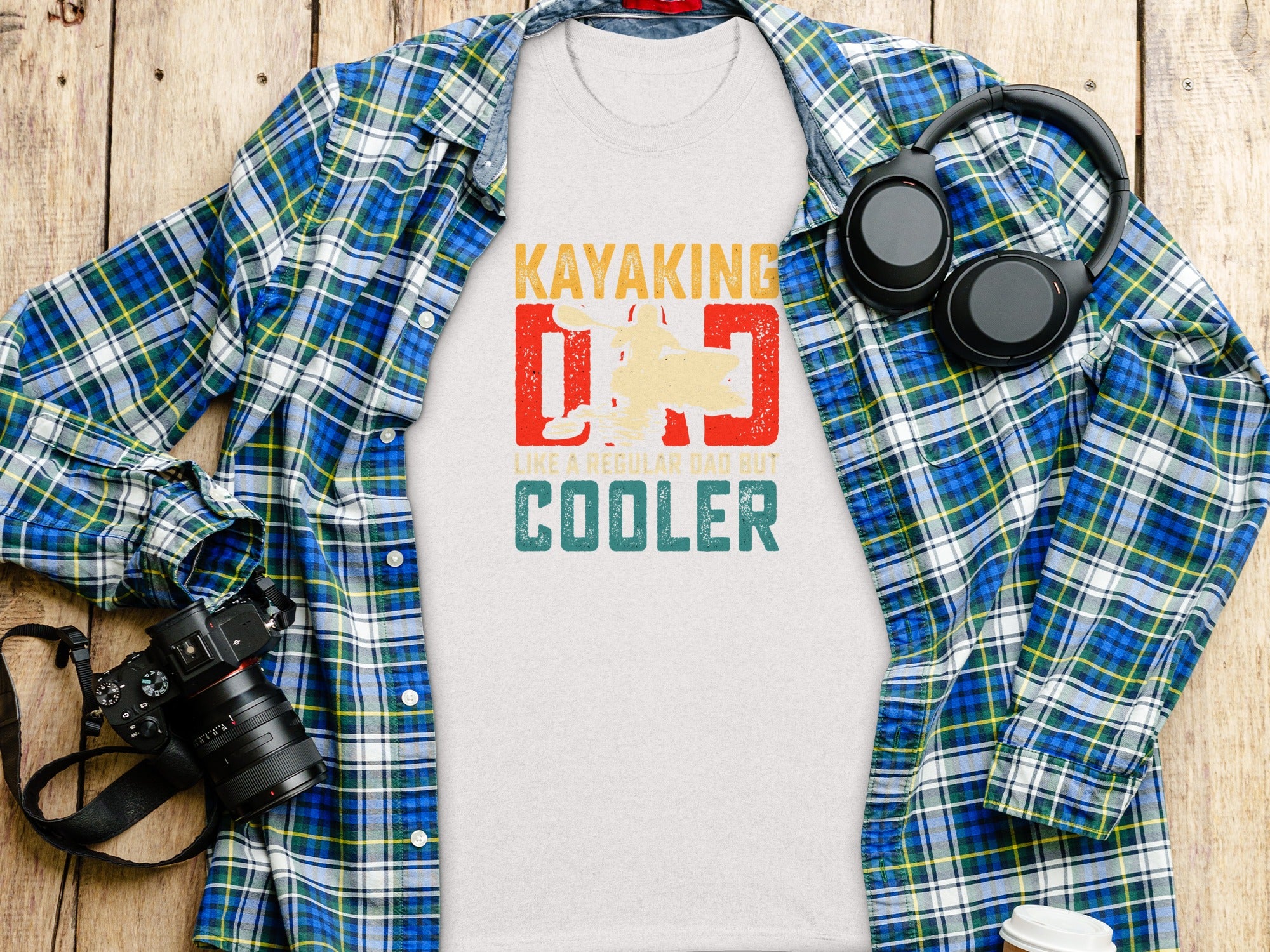 T-shirt with "Kayaking Dad Cooler" graphic, headphones, and camera.