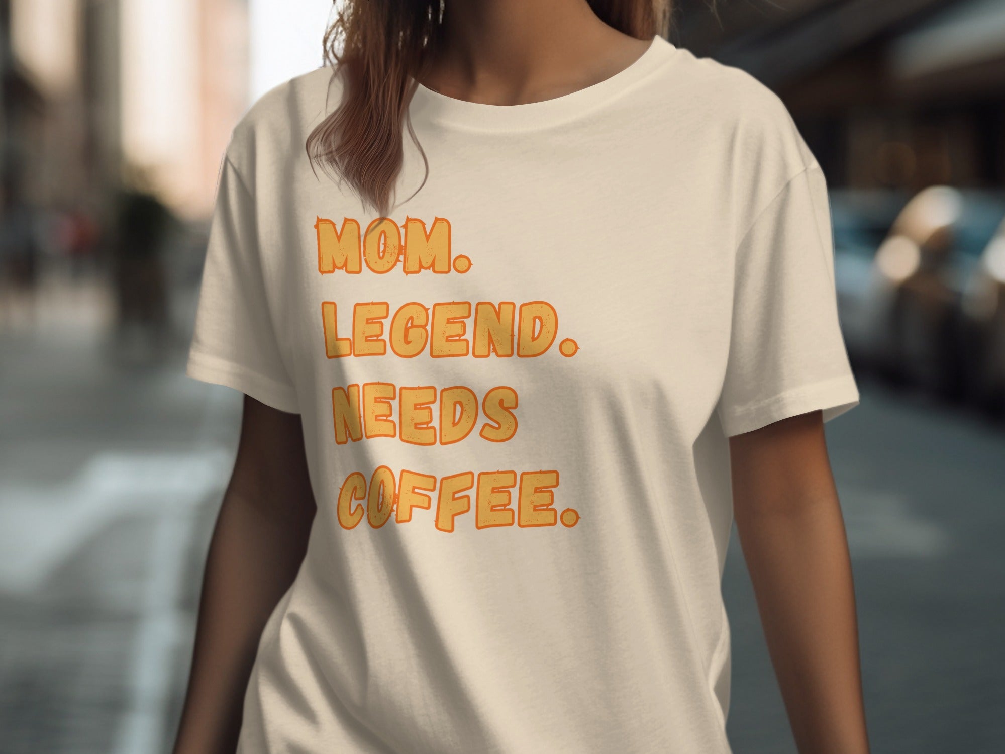 Cream t-shirt with orange text reading "MOM. LEGEND. NEEDS COFFEE."