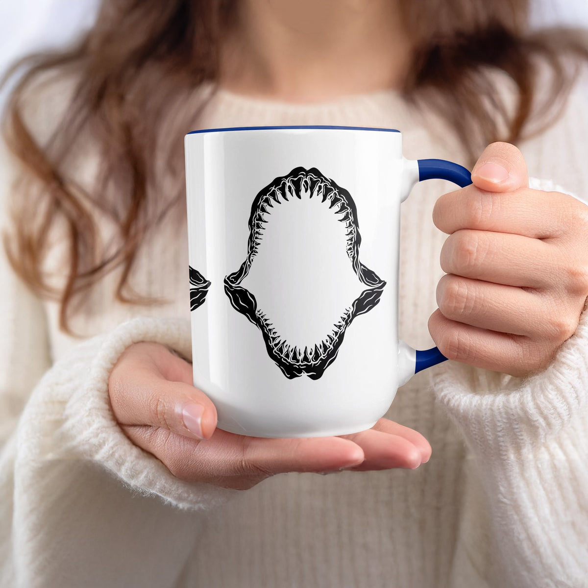 White mug with blue rim and handle featuring black shark jaw graphic.