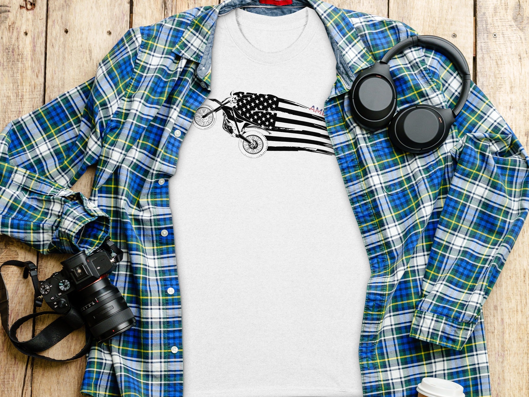 T-shirt with American flag motorcycle graphic, plaid shirt, headphones, and camera.