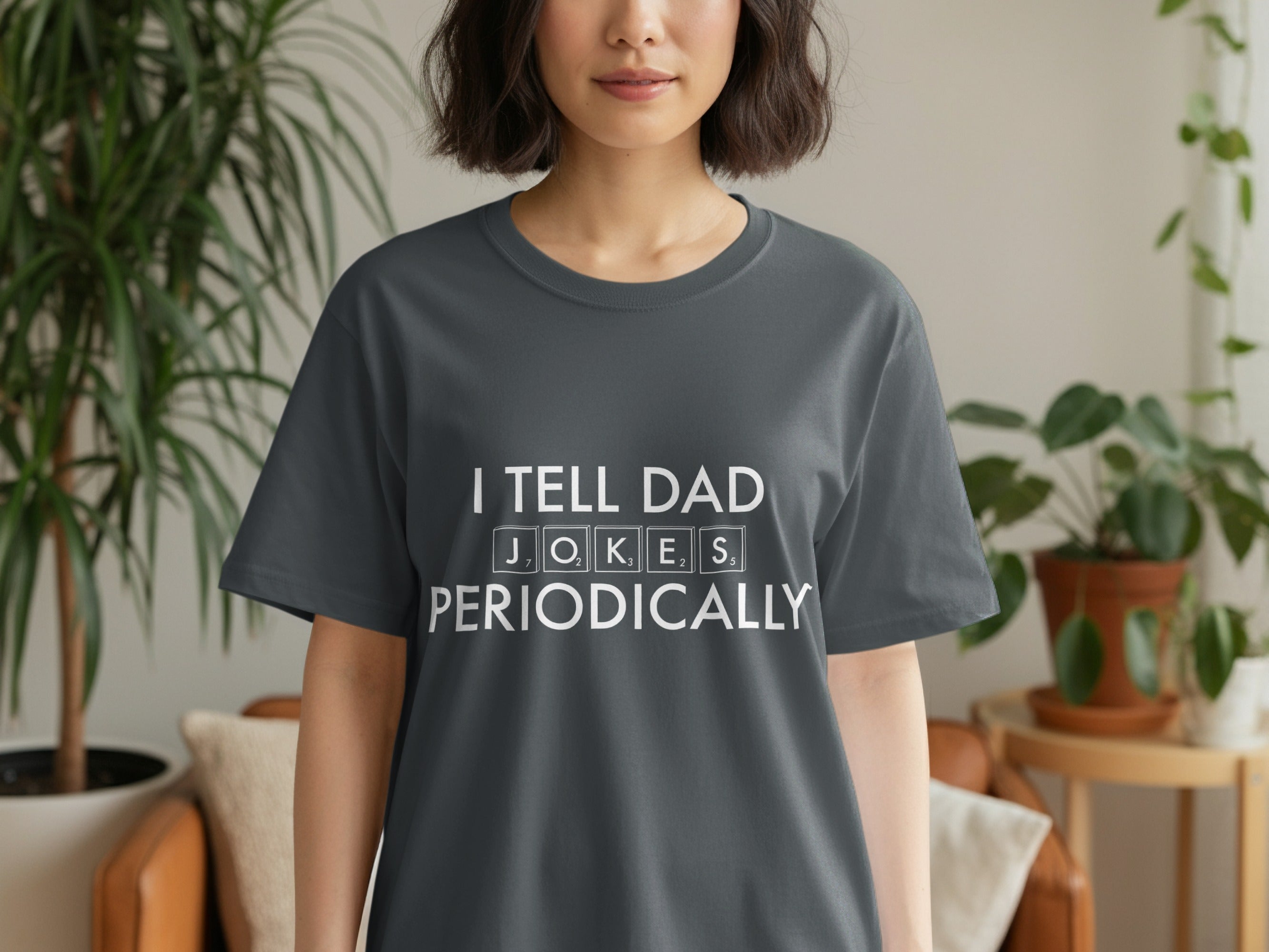 Dark grey t-shirt with white text reading "I TELL DAD J, O, K, E, S PERIODICALLY".