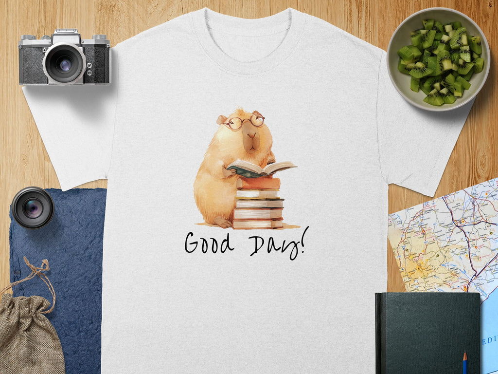 White t-shirt with watercolor capybara wearing glasses reading a book.