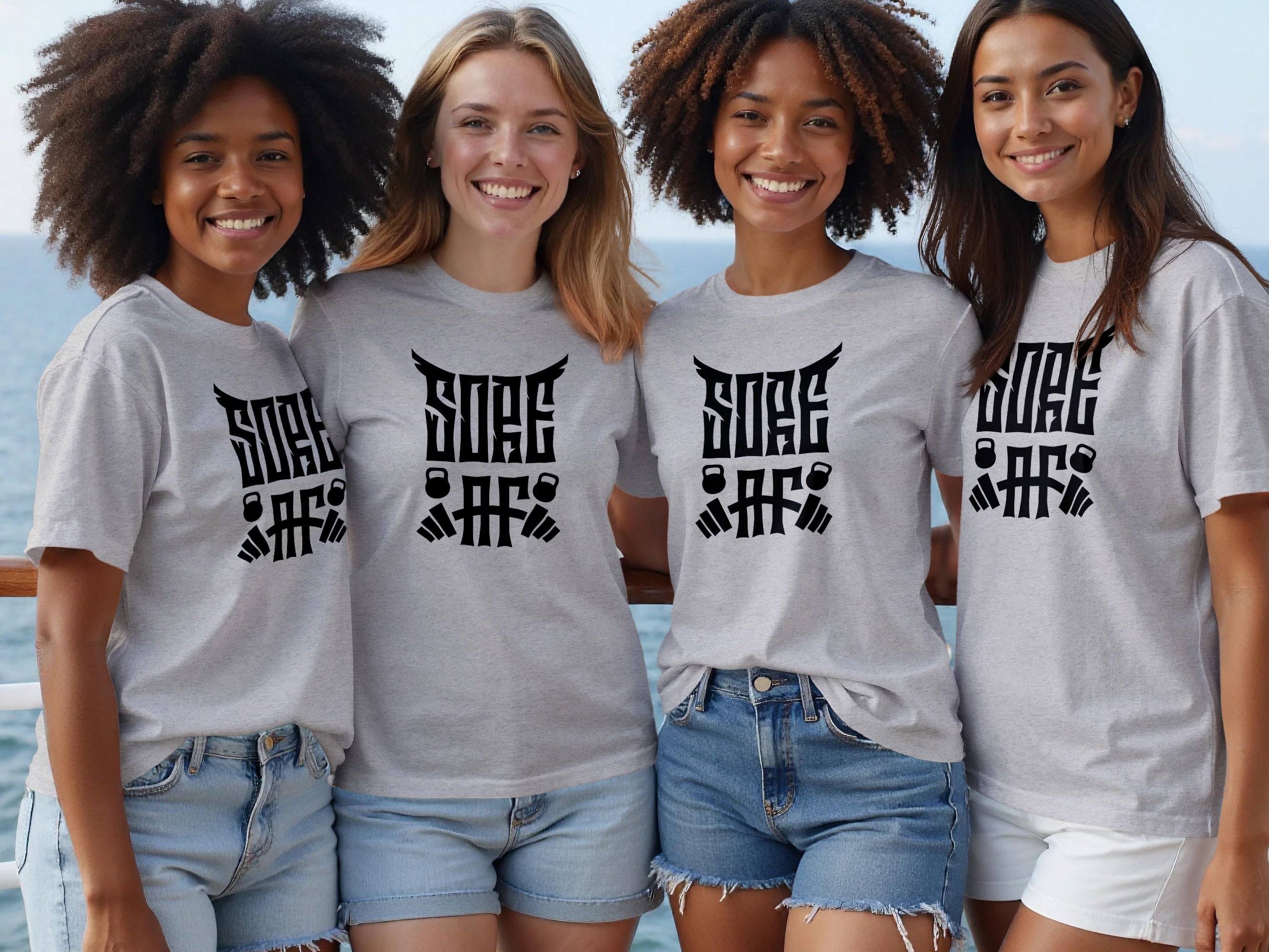Four women wearing grey t-shirts with black "Sore AF" graphic design featuring barbells and kettlebells.