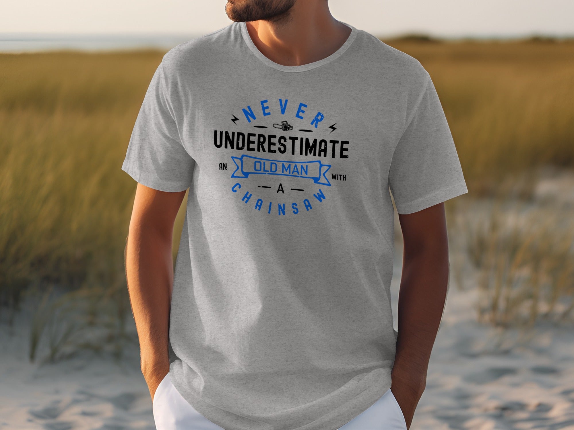 Grey t-shirt with "Never Underestimate an Old Man With a Chainsaw" graphic.