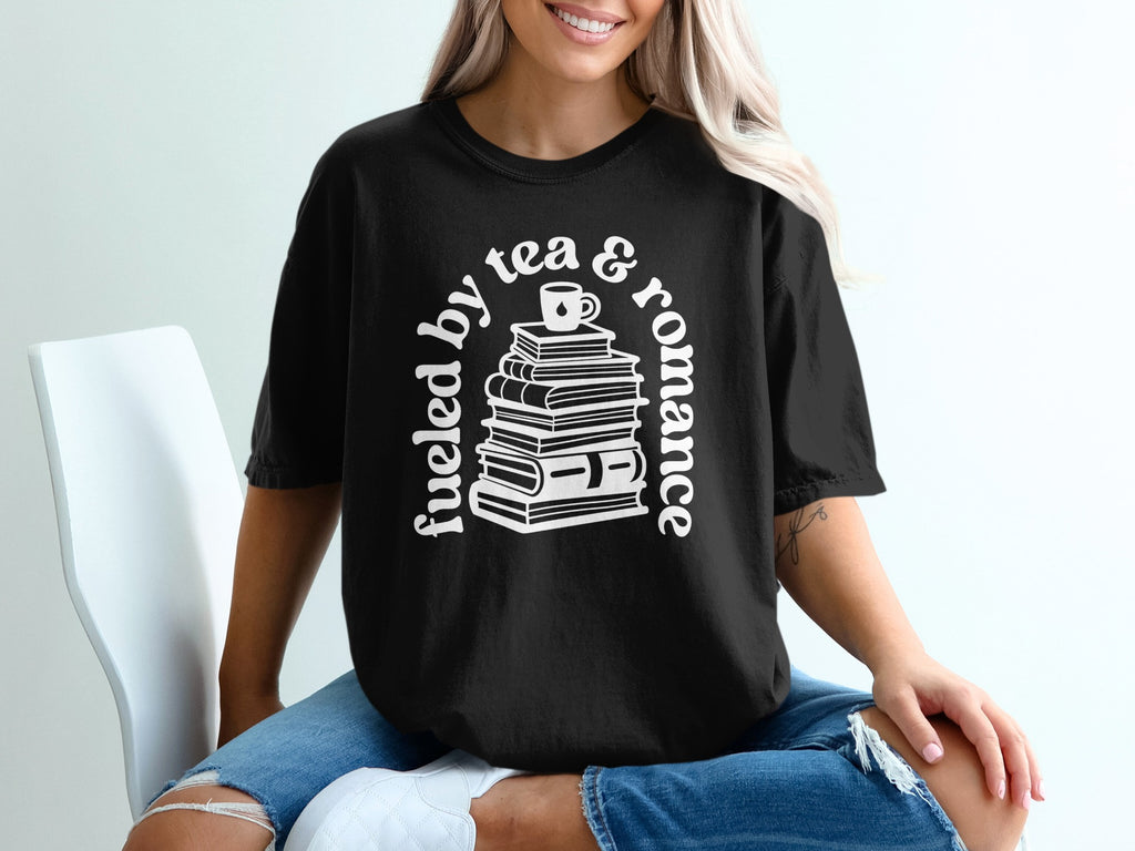 Black t-shirt with stack of books and cup, reads "fueled by tea & romance."