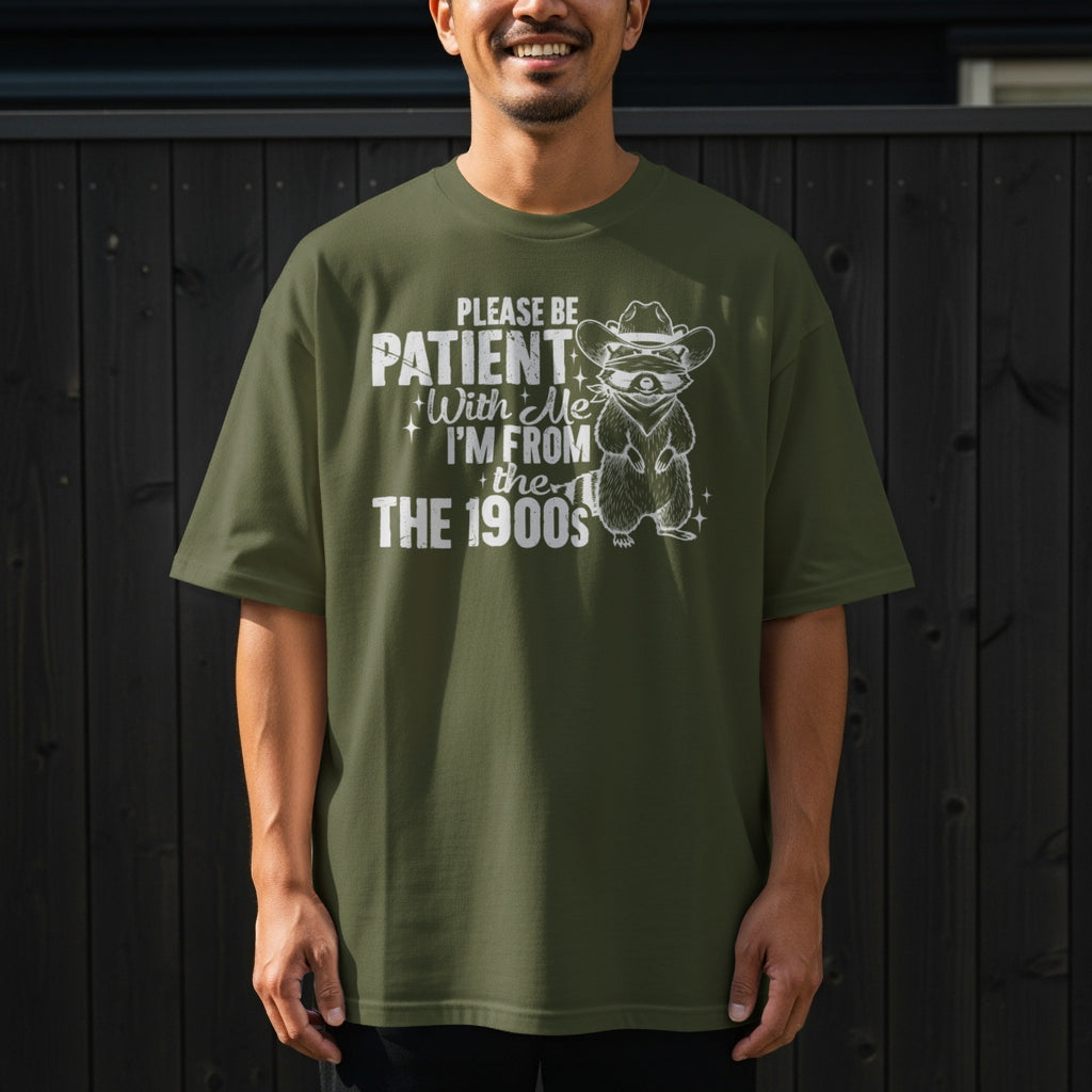 Green t-shirt with raccoon in cowboy hat graphic and text: Please be patient with me