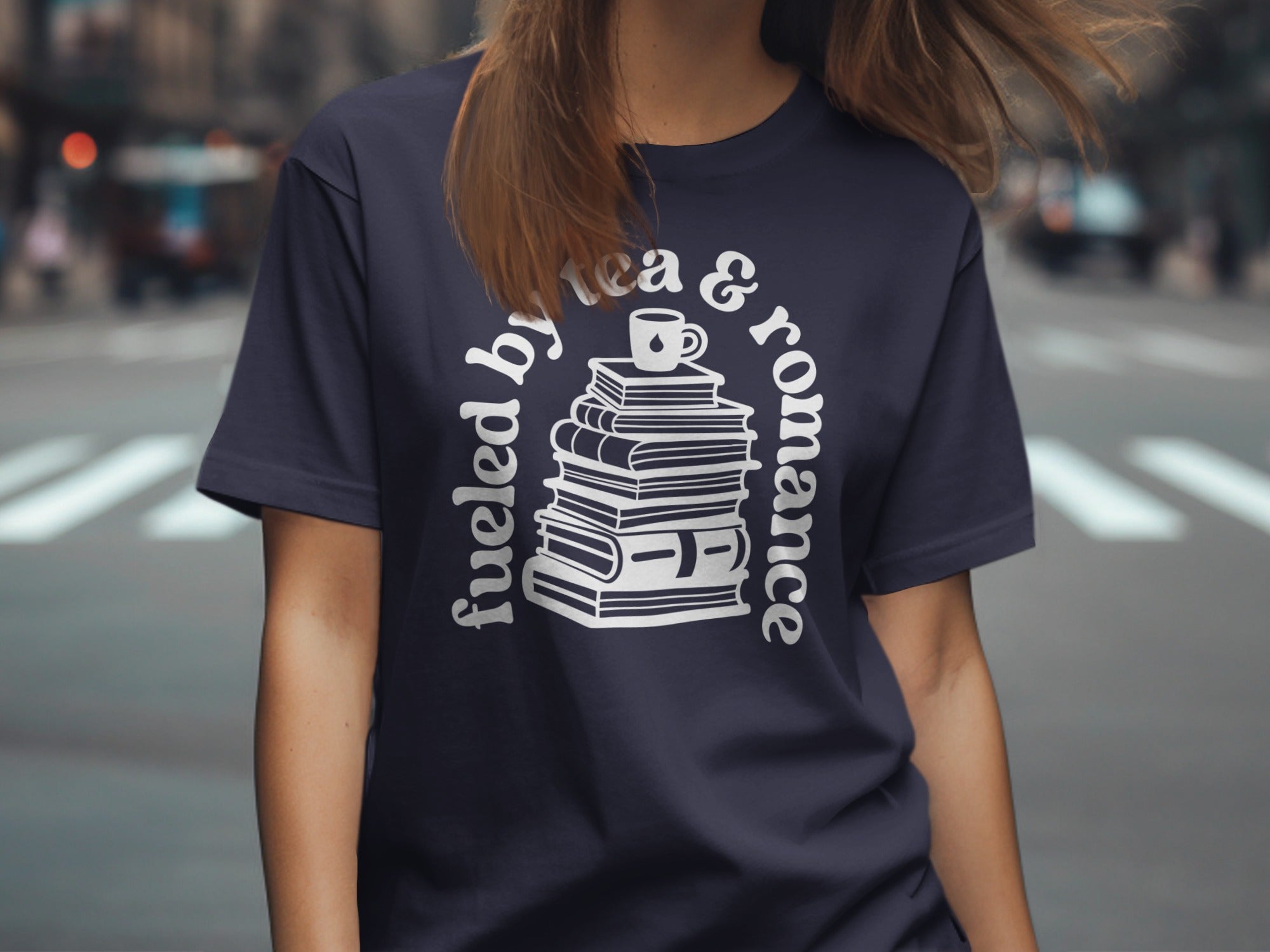 Navy t-shirt with "fueled by tea & romance" text and stacked books graphic.