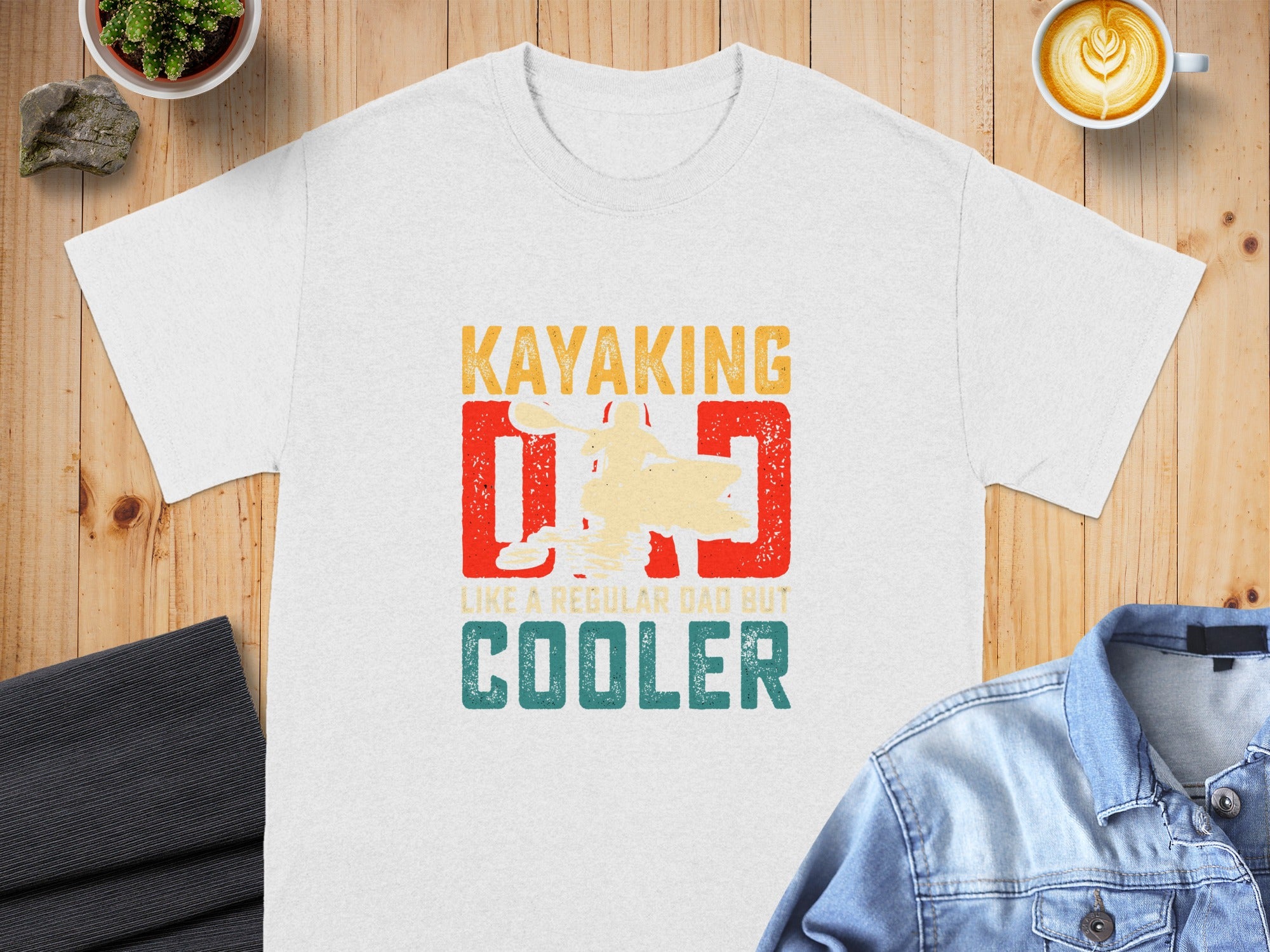 White t-shirt graphic "Kayaking Dad Like a Regular Dad But Cooler" with kayak image.