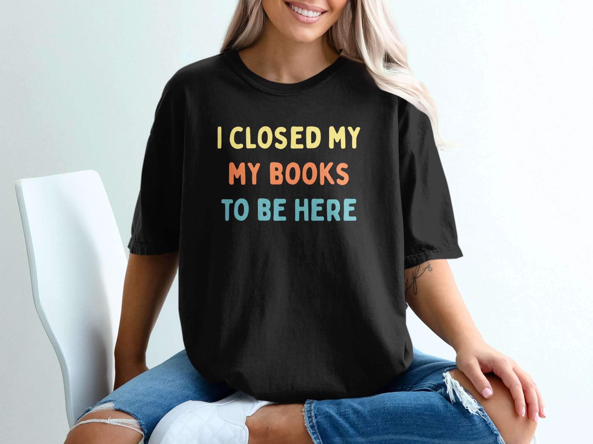 Black t-shirt with yellow, orange, and blue text: "I CLOSED MY MY BOOKS TO BE HERE"