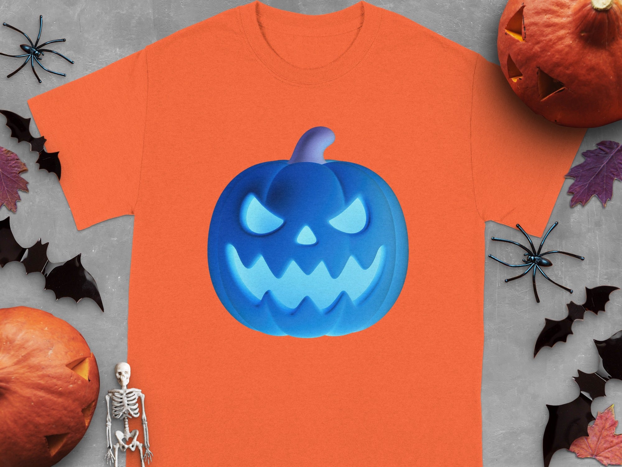 Orange t-shirt with a glowing blue jack-o'-lantern graphic on a Halloween-themed background.