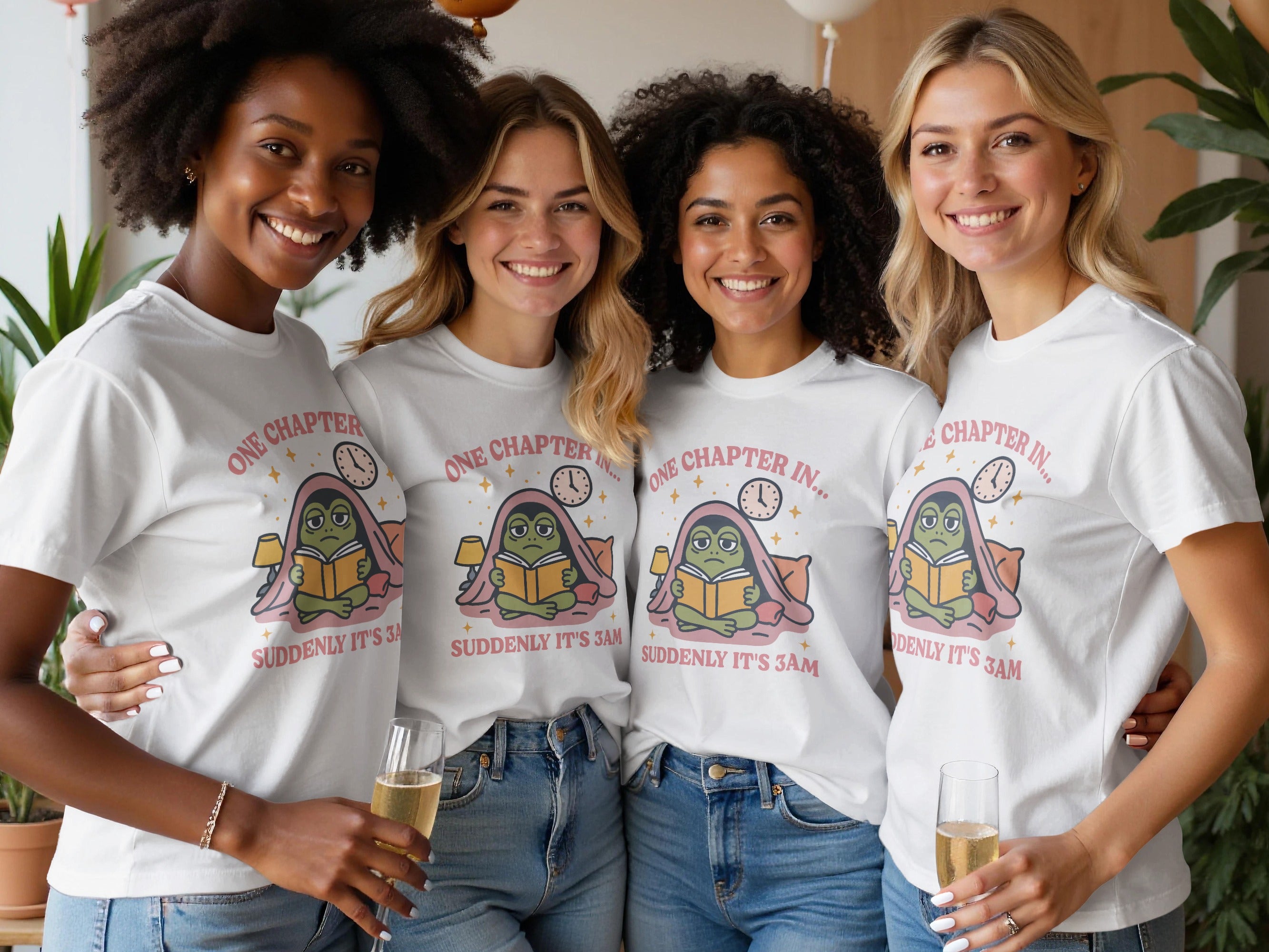 Four women in white t-shirts displaying a frog reading a book that says "One chapter in... Suddenly it's 3 am."