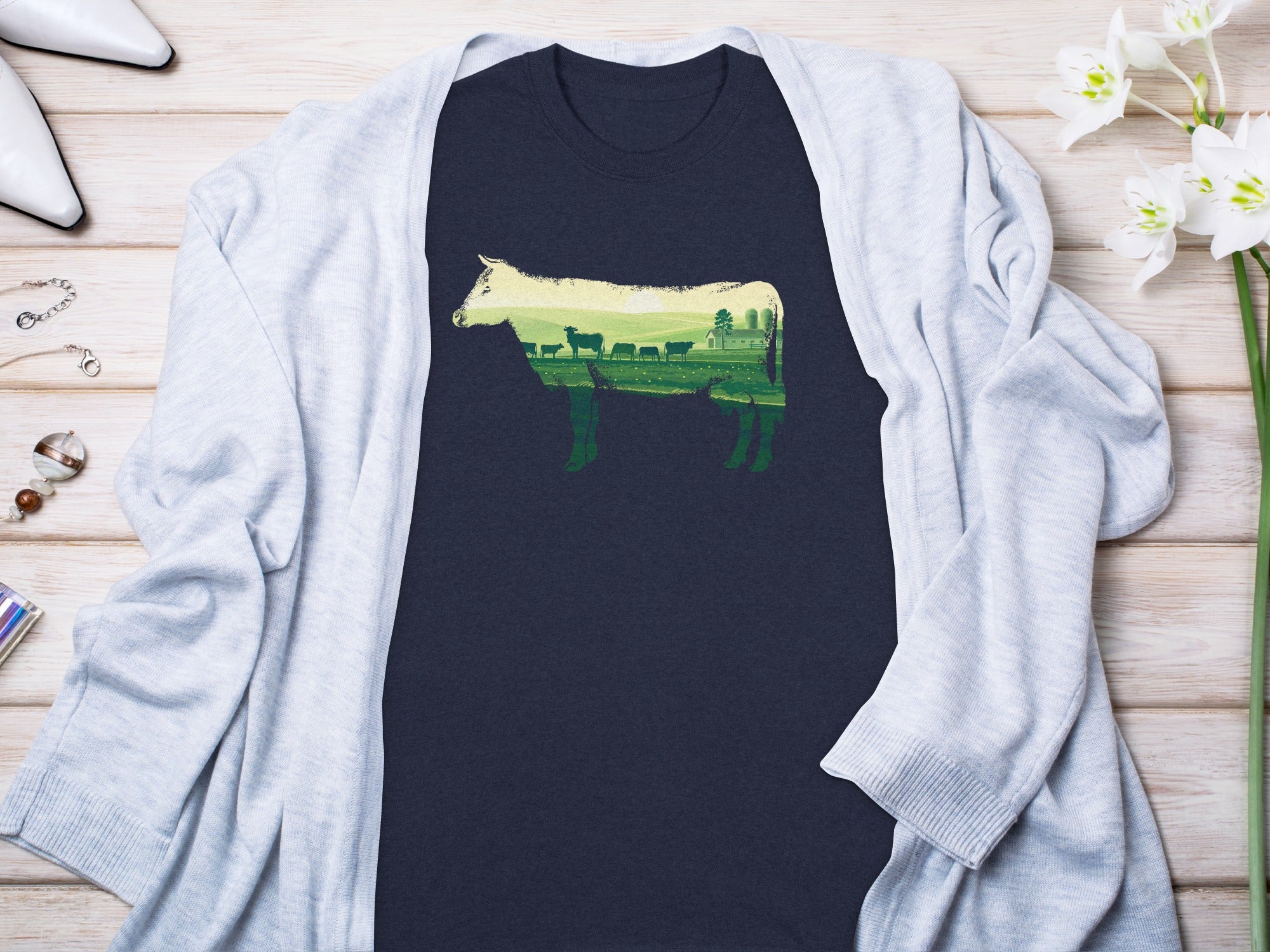Dark navy t-shirt featuring a cow silhouette filled with a green pastoral landscape.