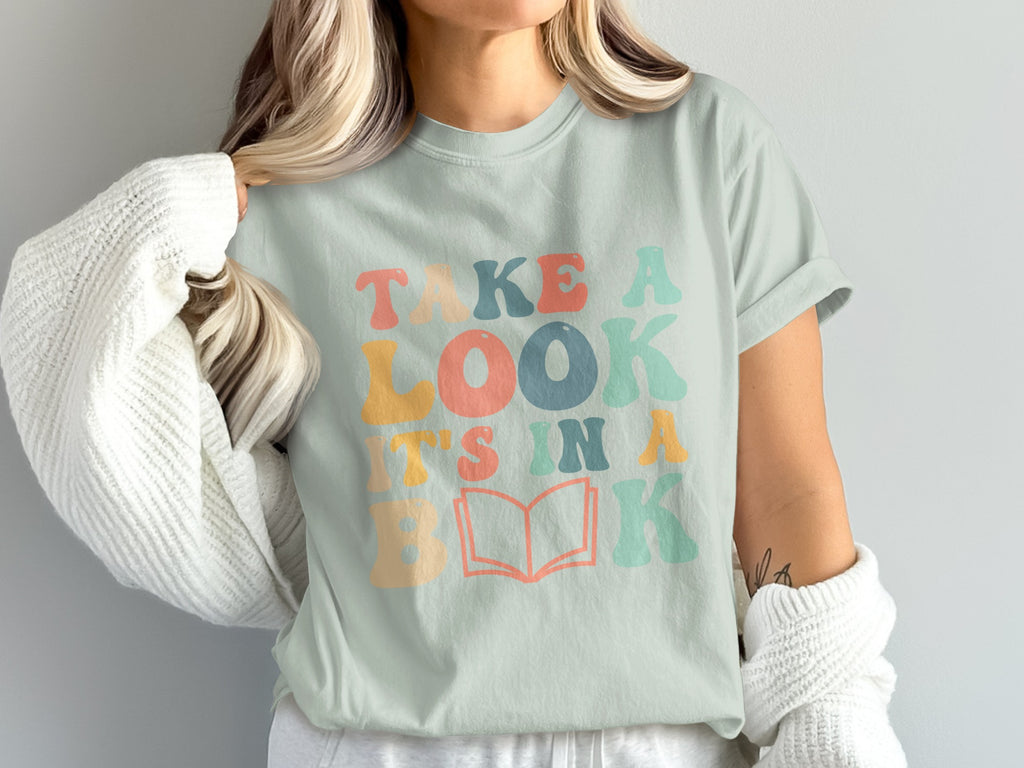 T-shirt with "Take a look, it's in a book" text and an open book graphic.