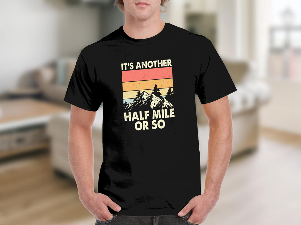 Black t-shirt with text "IT'S ANOTHER HALF MILE OR SO" and mountain graphic.