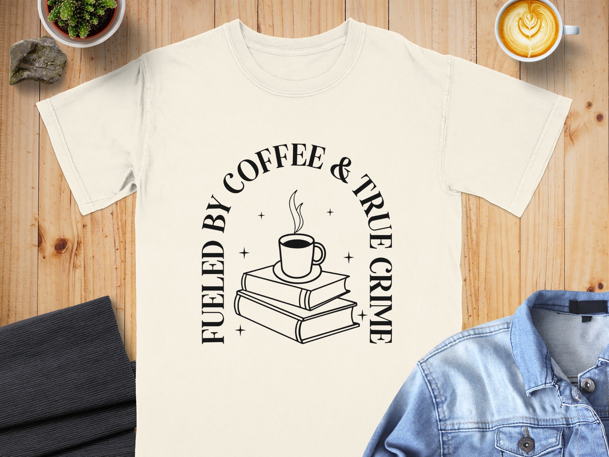Cream t-shirt with "Fueled by coffee & true crime" text and book and coffee cup graphic.