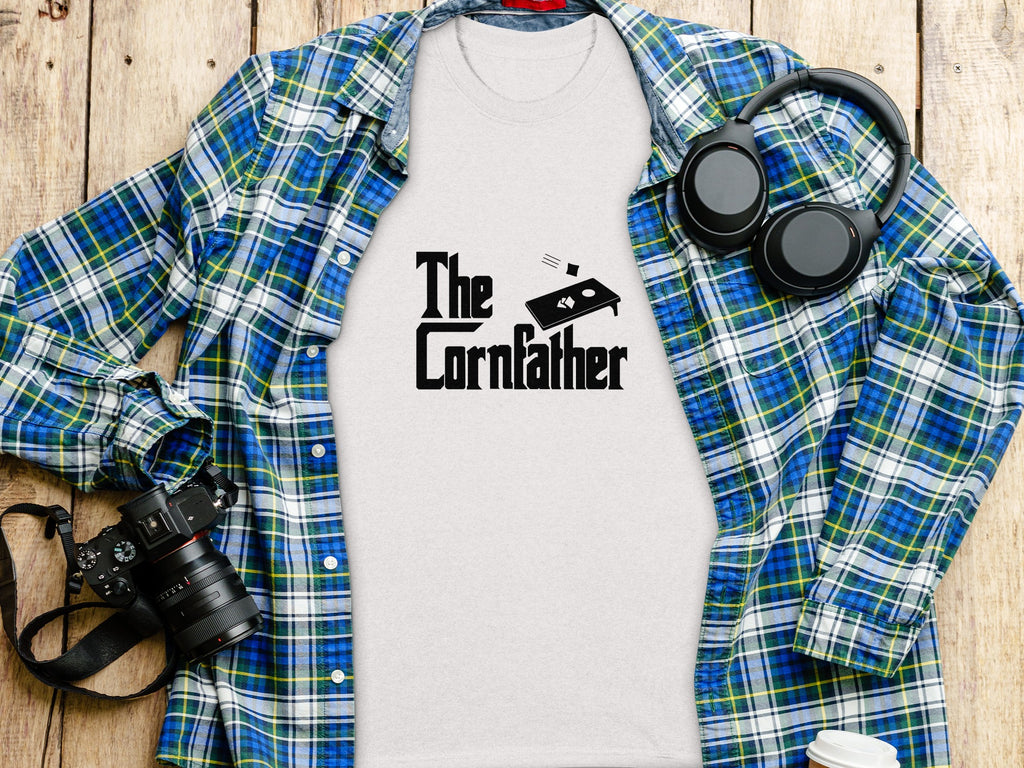 White t-shirt with "The Cornfather" text and cornhole board graphic.