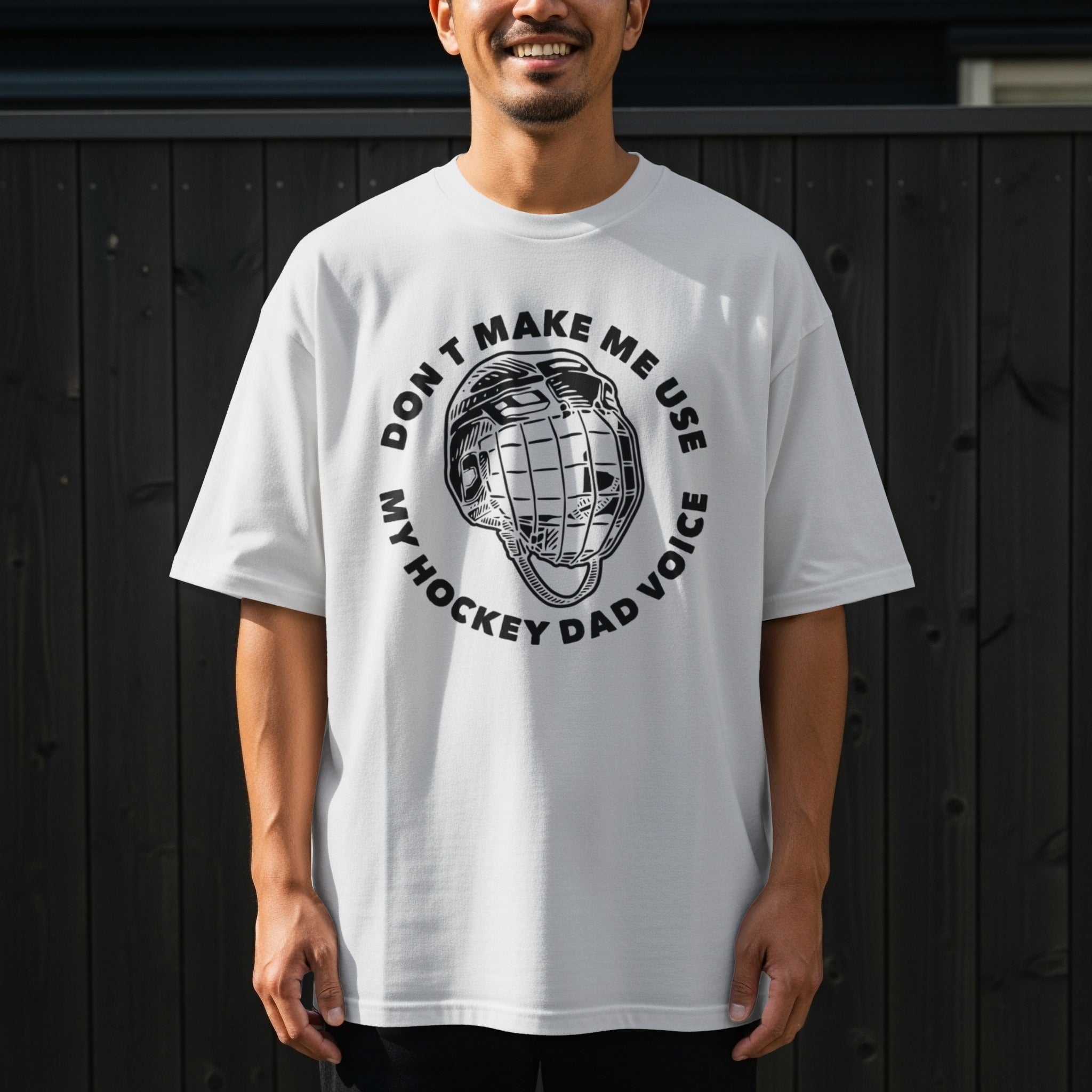 White t-shirt with black text and hockey helmet graphic saying "Don't Make Me Use My Hockey Dad Voice".