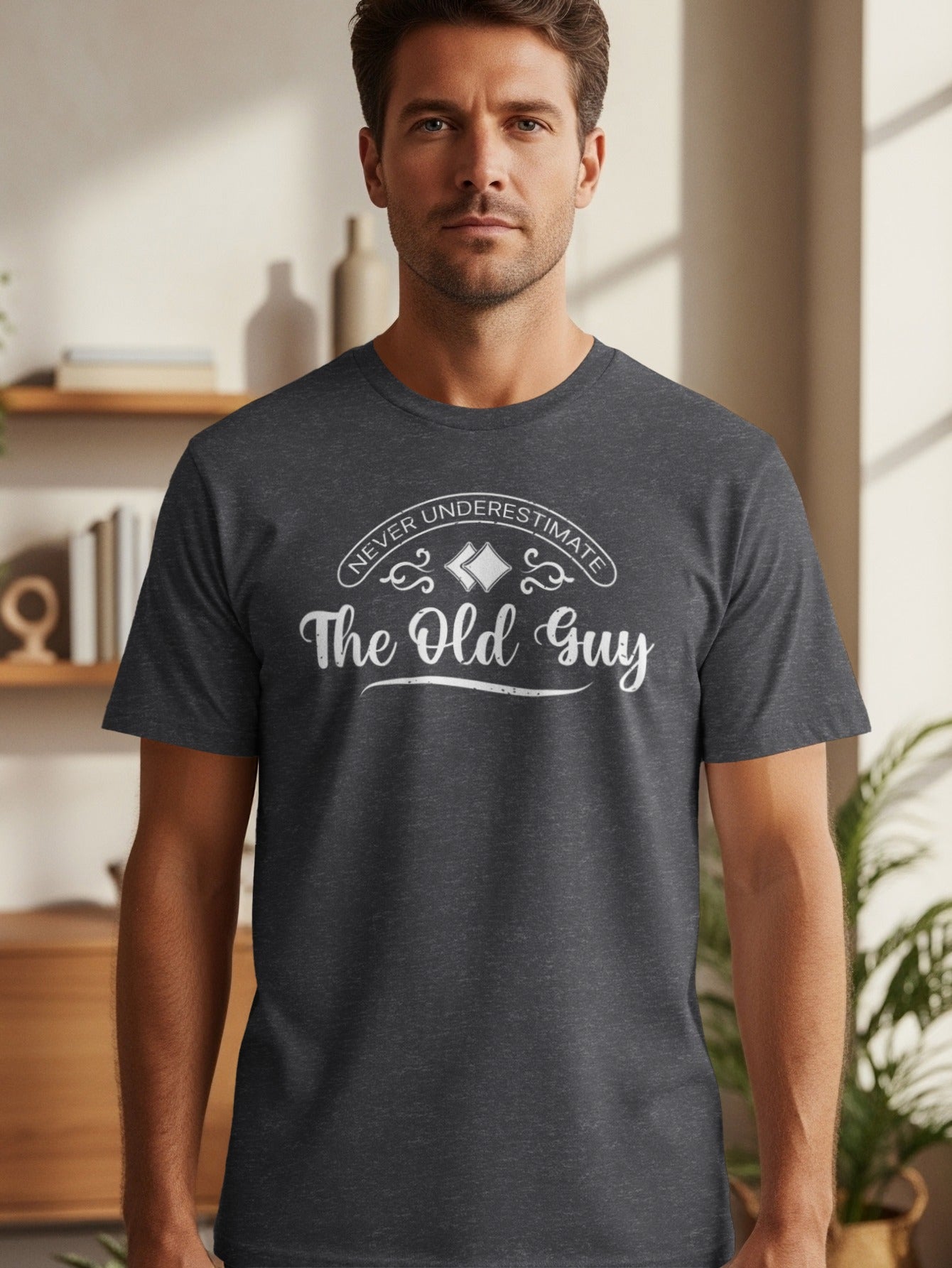 Dark grey t-shirt with white text "Never Underestimate The Old Guy".