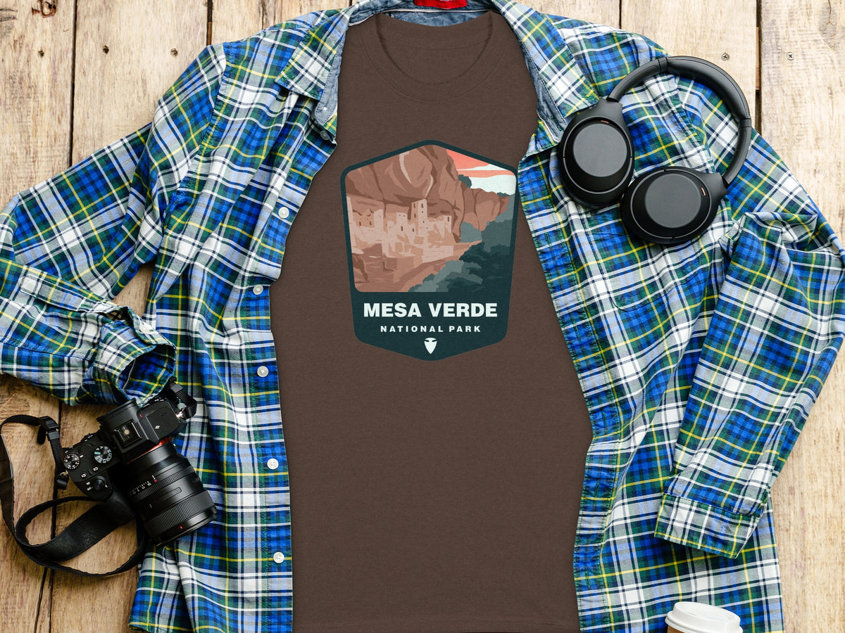 Brown t-shirt with Mesa Verde National Park graphic, a plaid shirt, and headphones.