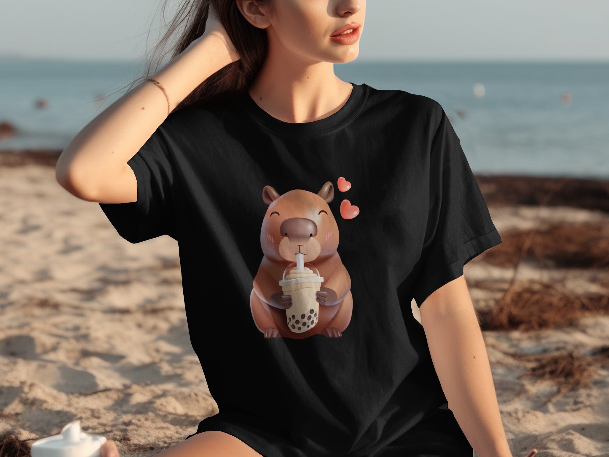 Black t-shirt with a cartoon capybara drinking bubble tea and pink hearts.