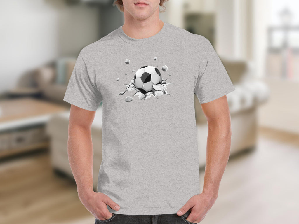 Grey t-shirt featuring a graphic of a soccer ball breaking through cracked ground.