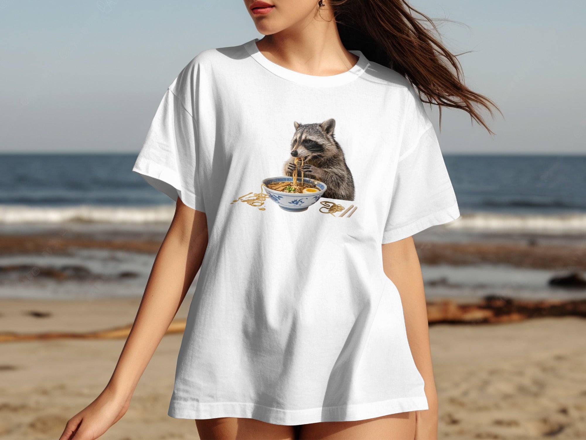 White t-shirt with a raccoon eating ramen noodles graphic on the chest.