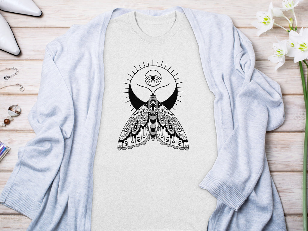 Light gray t-shirt with black moth and eye graphic, laid flat with cardigan.
