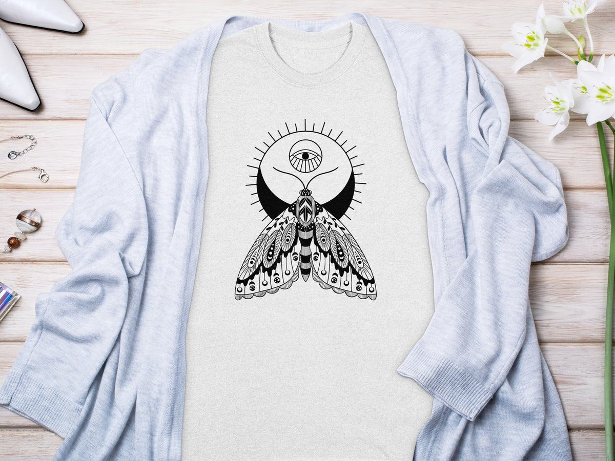 Light gray t-shirt with black moth and eye graphic, laid flat with cardigan.