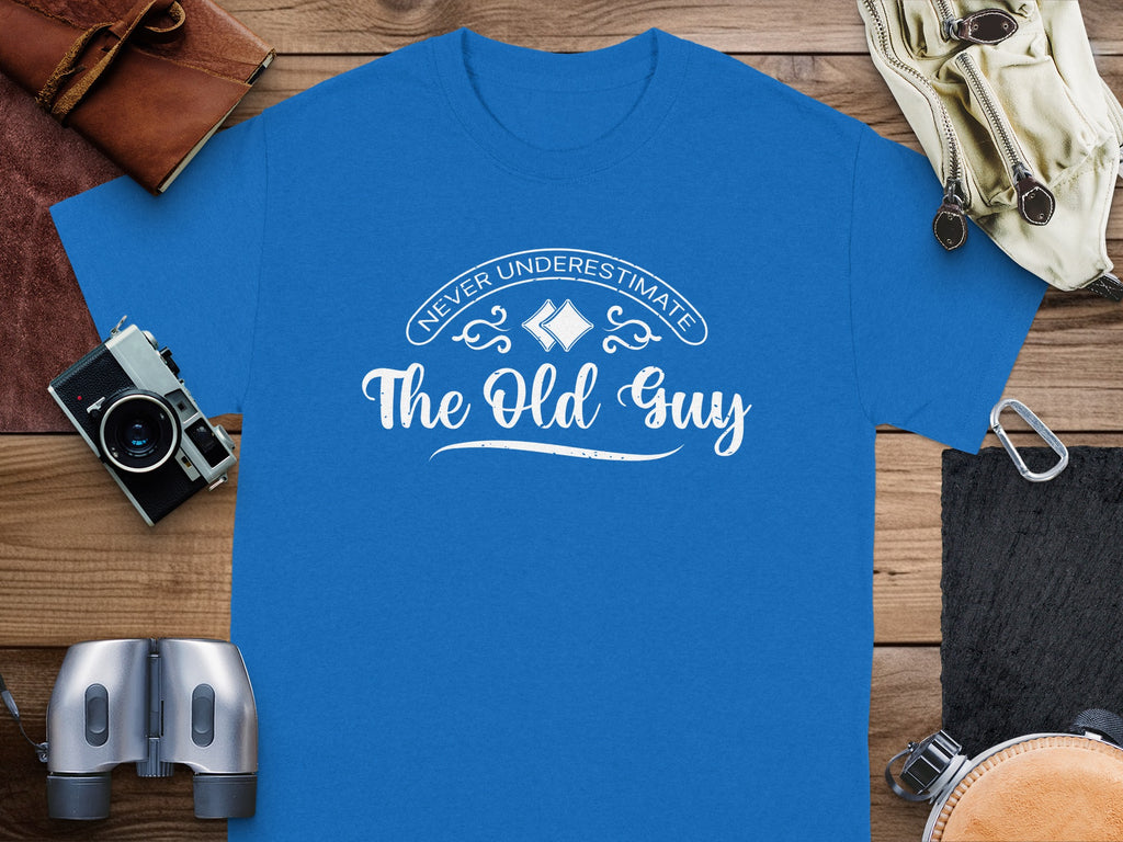 Blue t-shirt with white text "Never Underestimate The Old Guy" and decorative elements.