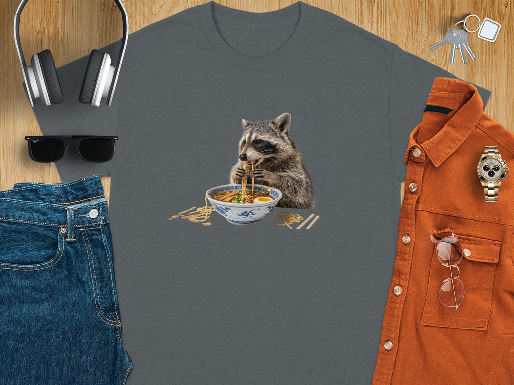 Raccoon eating ramen noodles from a bowl, on a gray t-shirt.