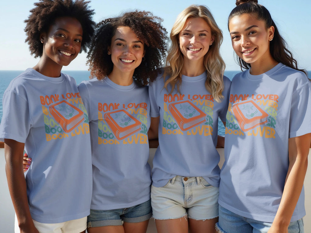 Four women smile wearing light blue t-shirts with a "Book Lover" graphic.
