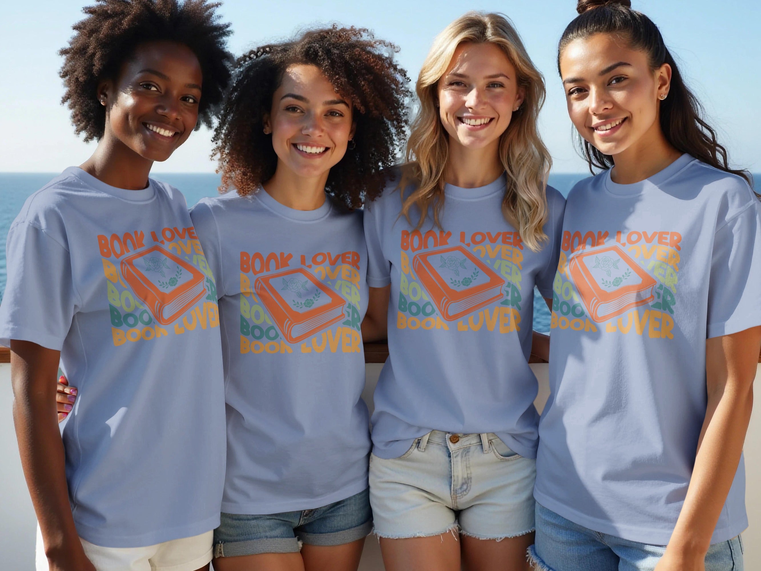 Four women smile wearing light blue t-shirts with a "Book Lover" graphic.