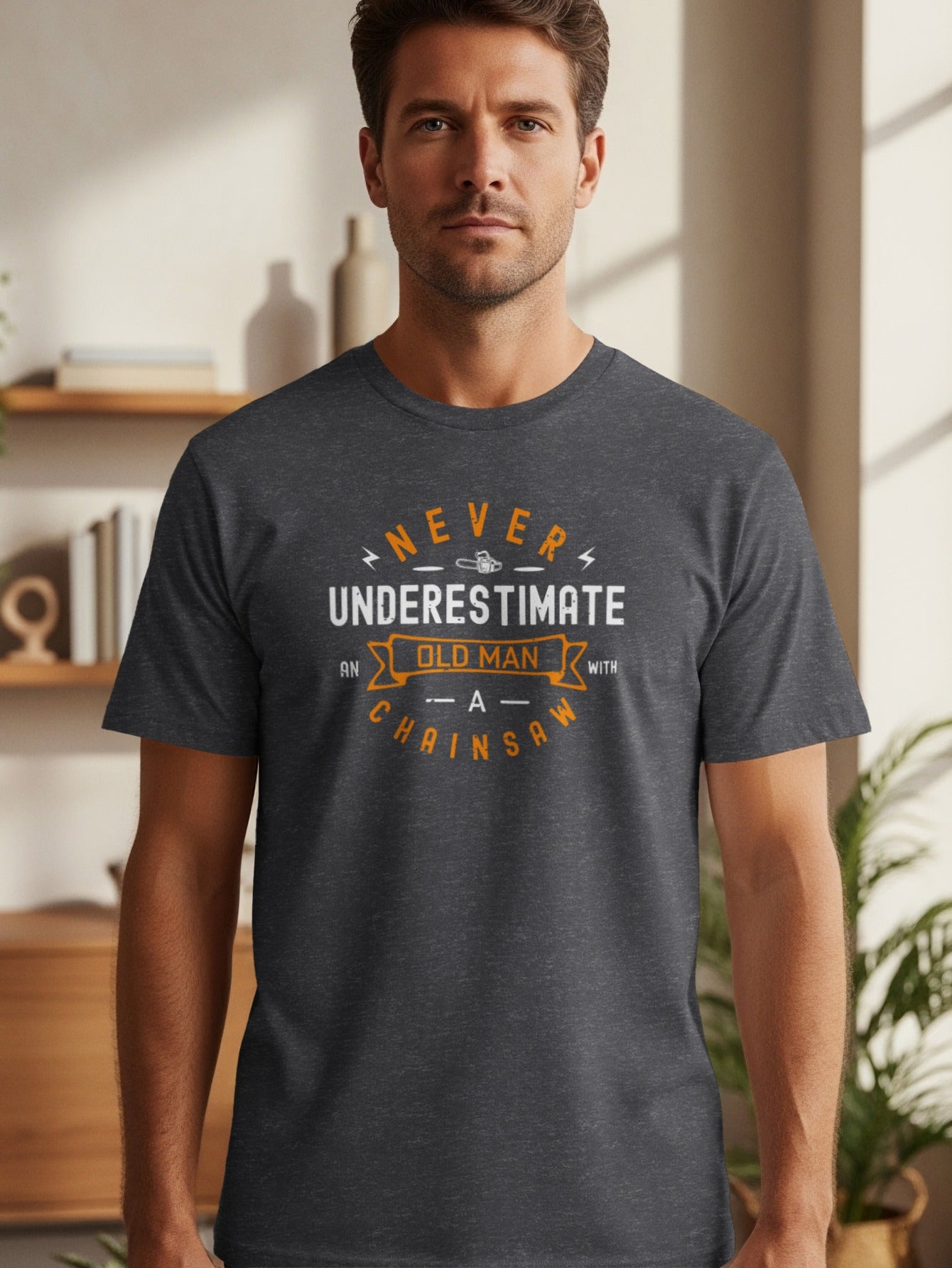 Dark grey t-shirt with "Never Underestimate an Old Man With A Chainsaw" text design.