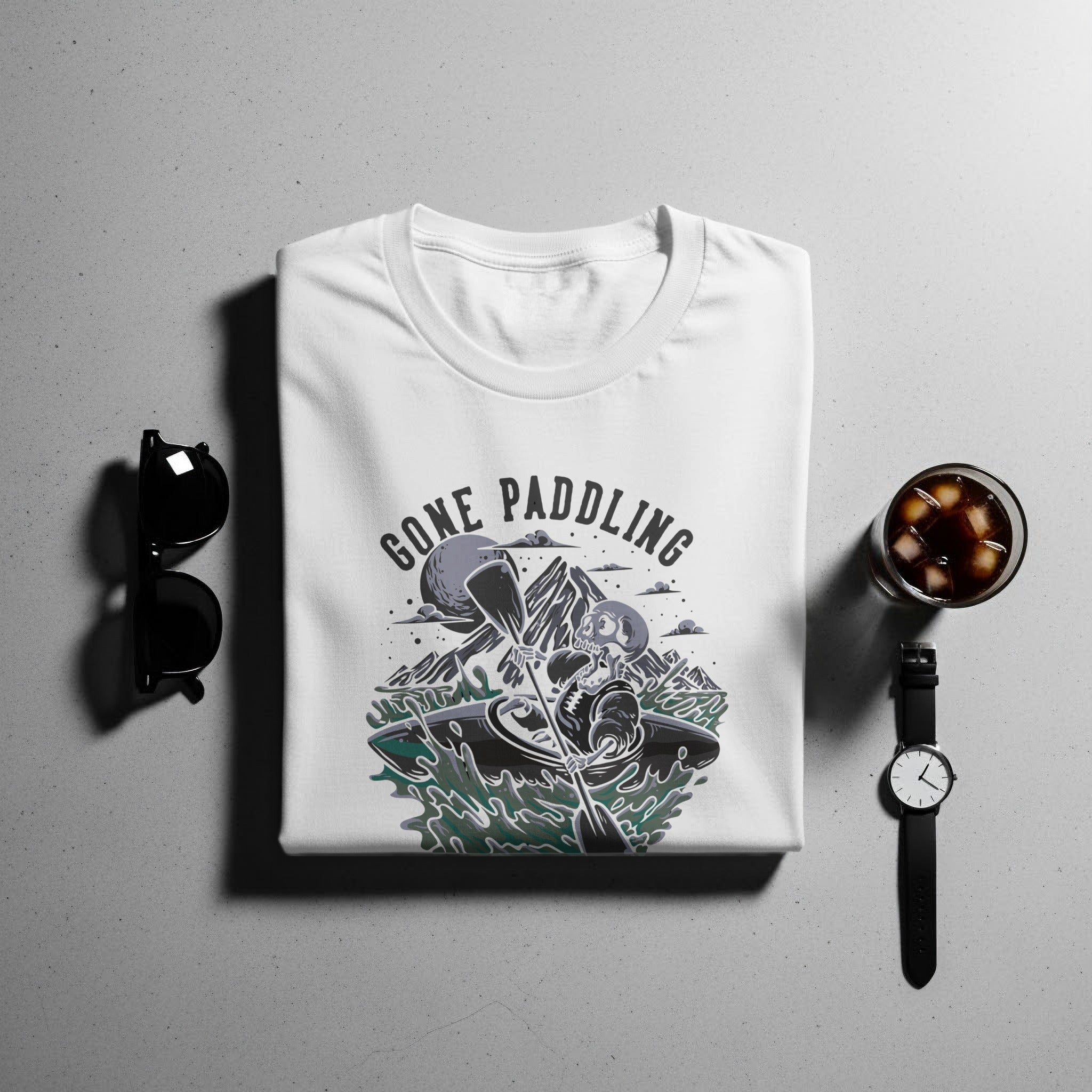 White t-shirt with a skeleton kayaking graphic and the text "GONE PADDLING"