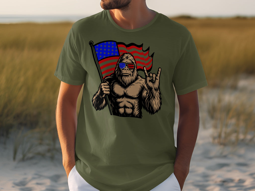 Bigfoot with sunglasses holds a waving US flag and throws a rock-on hand sign.