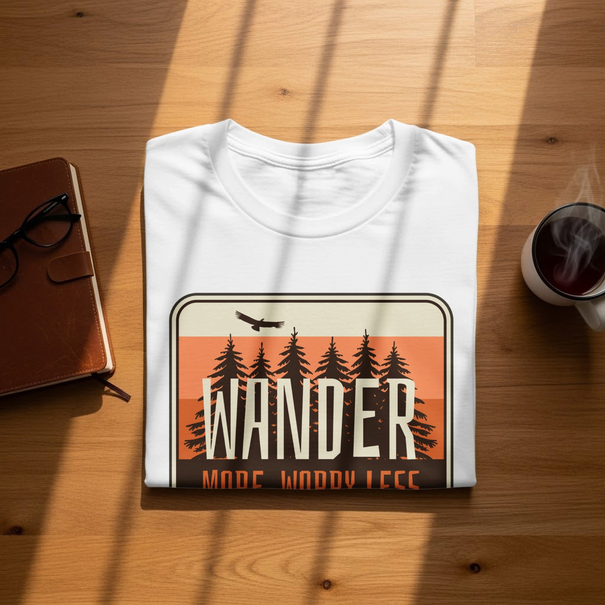White t-shirt with "Wander" text and pine trees graphic.