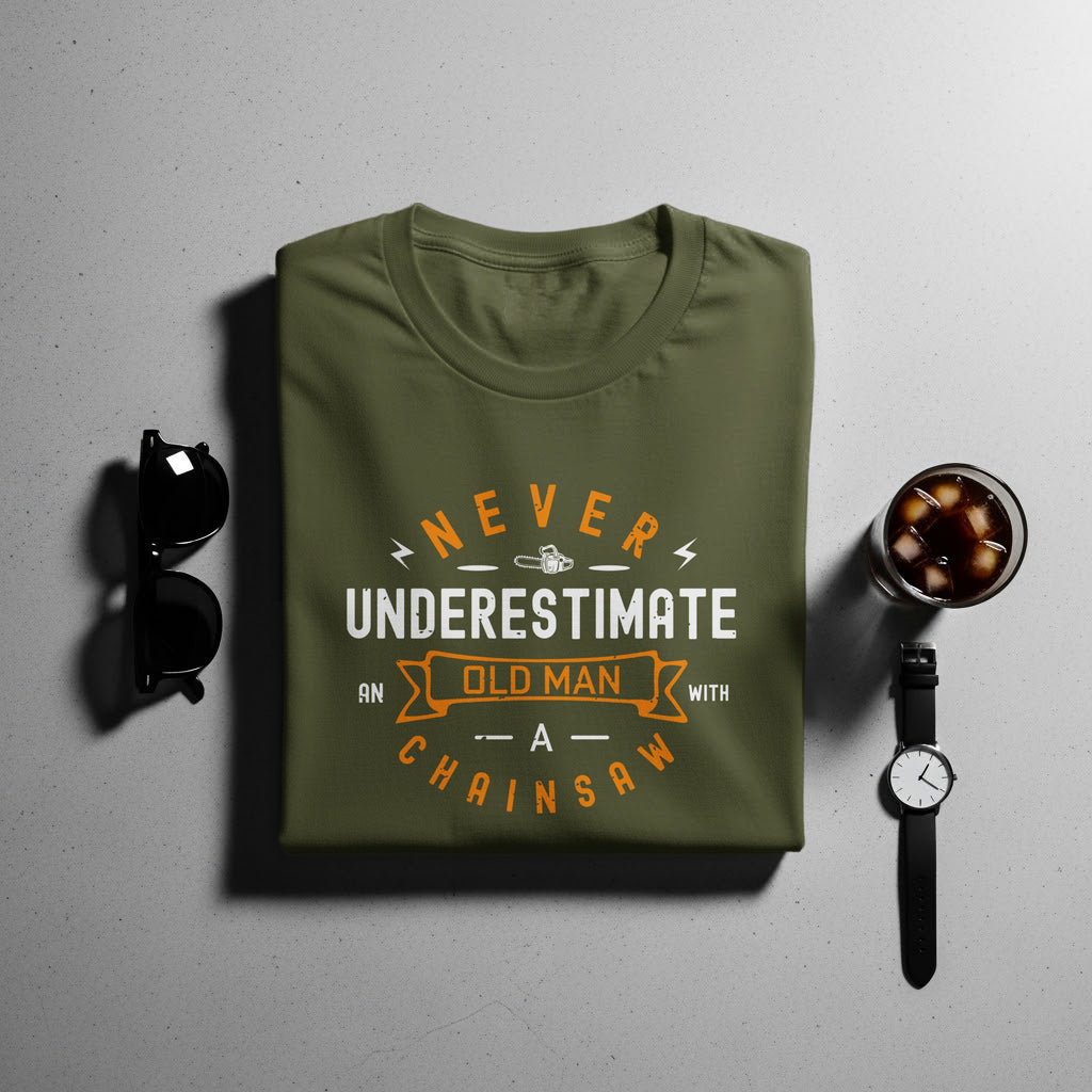 Olive green t-shirt with "Never Underestimate An Old Man With A Chainsaw" graphic.